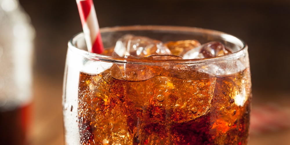 Cola soft drink in glass with striped straw