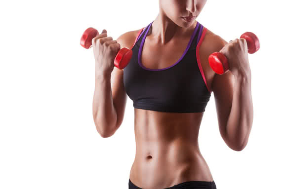 Torso of a young fit woman lifting dumbbells